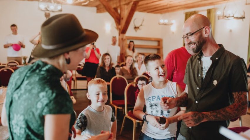 A lively indoor gathering with adults and children enjoying a friendly interaction in a warmly lit room.